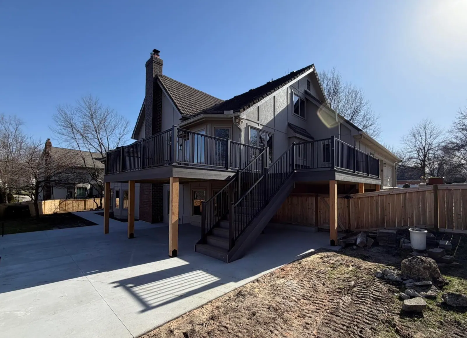 Elevated backyard deck with new stairs, a landing, and black metal railings on a Kansas City area home